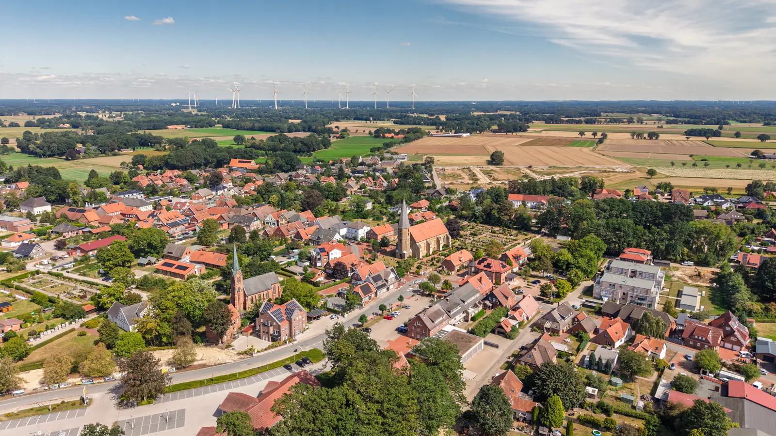 Luftaufnahme vom Ortskern Badbergen im Artland mit seinen beiden Kirchen, umgeben von Feldern
